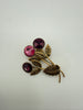 Vintage Austrian floral brooch with three faceted pink and purple crystals and textured gold-tone leaves