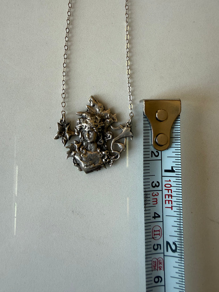 Sterling silver maiden pendant photographed beside measuring tape