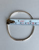 Vintage sterling silver hinged bangle beside measuring tape showing width