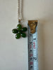 Green jade flower pendant shown beside measuring tape for scale