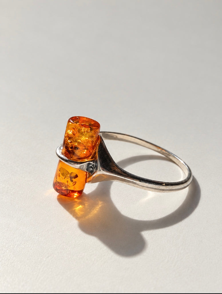 Close-up of cognac Baltic amber cylinder in open silver ring setting