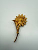 Back of vintage gold tone flower brooch showing metal construction long stem and pin-back closure