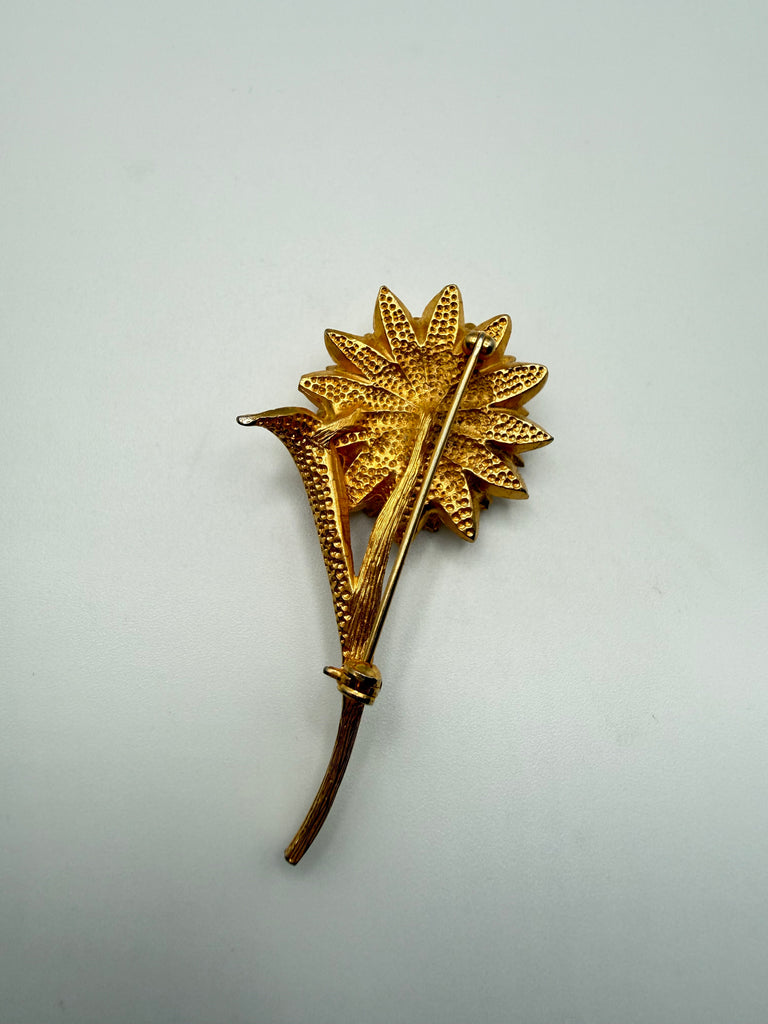 Back of vintage gold tone flower brooch showing metal construction long stem and pin-back closure
