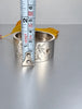 Antique sterling silver hinged bangle shown beside measuring tape