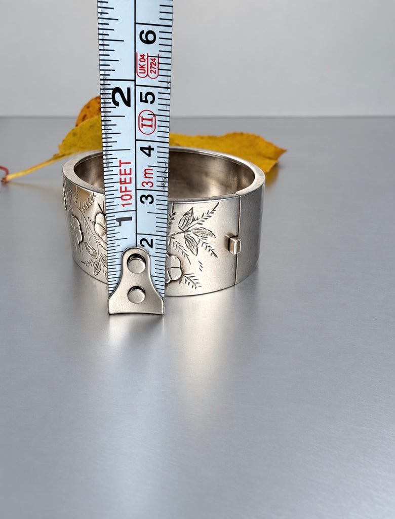 Antique sterling silver hinged bangle shown beside measuring tape