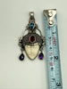 Vintage Balinese goddess sterling silver pendant beside measuring tape showing approximately 2 3/8 inch length