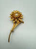 Vintage gold tone flower brooch with layered petals faux pearl centre and long stem