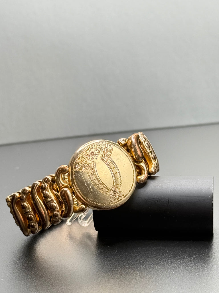 Close-up of vintage sweetheart bracelet showing unmonogrammed floral engraved centre medallion. 