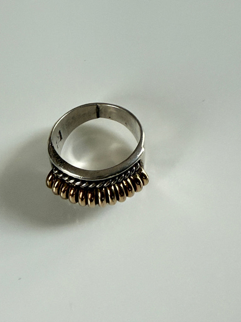 Vintage sterling silver ring showing dimensional ribbed design and gold-tone accents