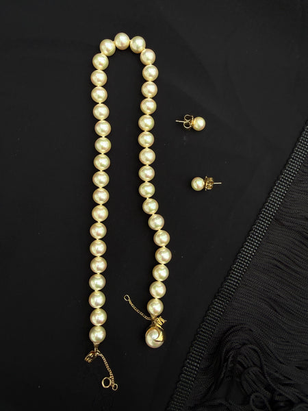 Vintage Majorica buttery yellow pearl necklace with matching gold-tone stud earrings displayed on black fabric.