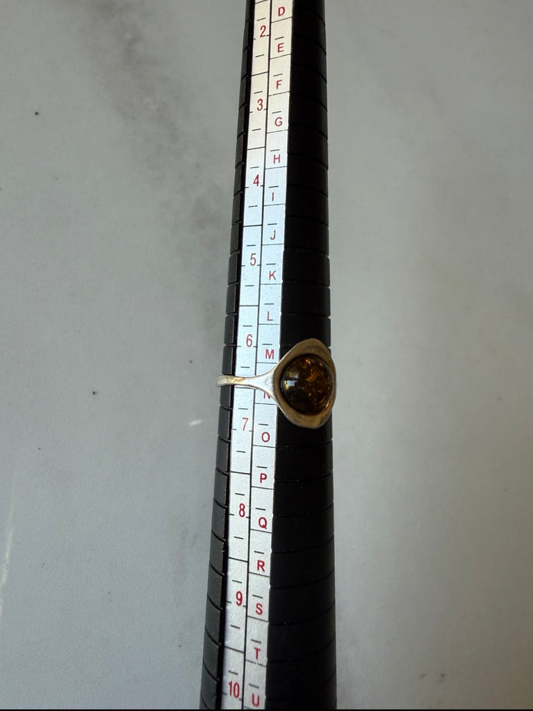 Vintage amber ring shown with measuring tool for size reference