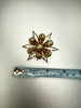 Vintage gold-tone pearl flower brooch beside measuring tape showing approximately 2.25 inch size