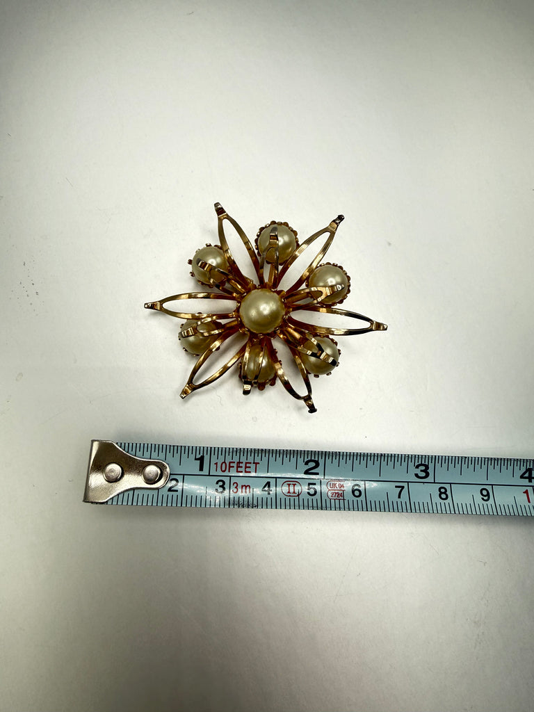 Vintage gold-tone pearl flower brooch beside measuring tape showing approximately 2.25 inch size