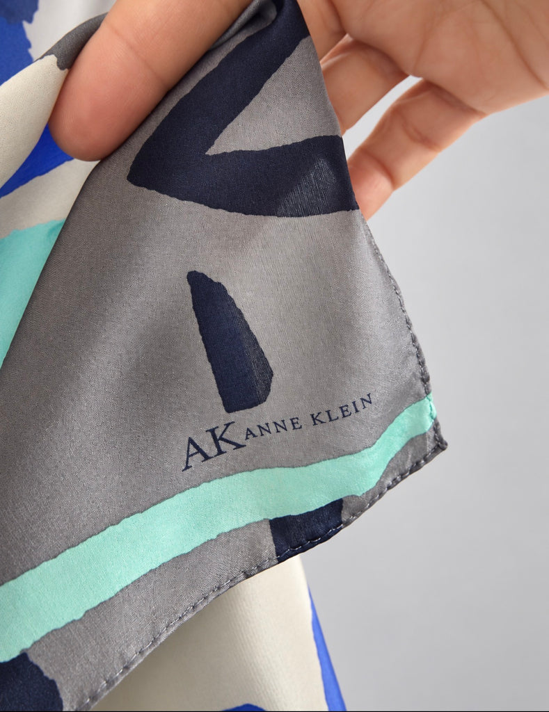 Close-up of "Anne Klein" printed on abstract blue grey and turquoise pattern