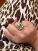 Genuine ammolite statement ring worn on hand showing wide sterling silver band and vivid green gemstone