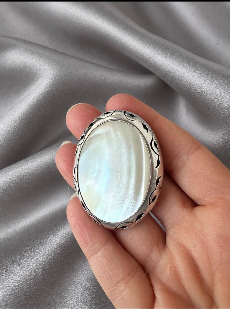 Oval mother of pearl sterling silver brooch pendant held in hand