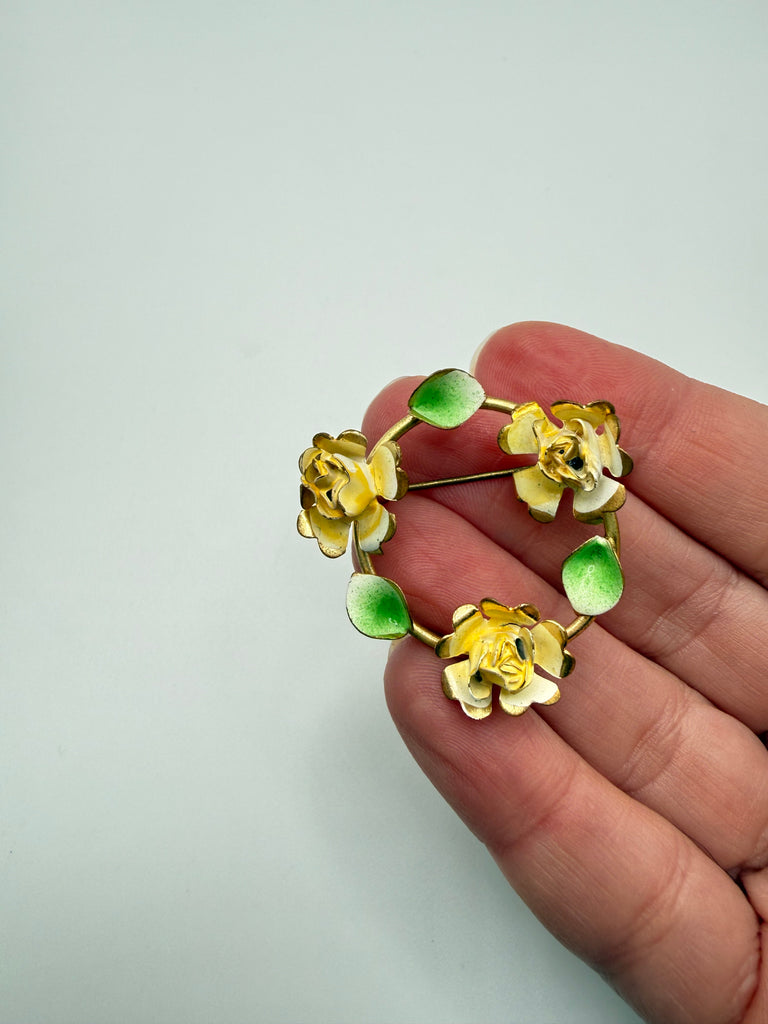 Close-up of vintage yellow rose brooch showing dimensional hand-painted flowers and green leaves