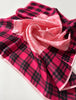 Close-up of vintage pink scarf showing black plaid border and pale botanical pattern