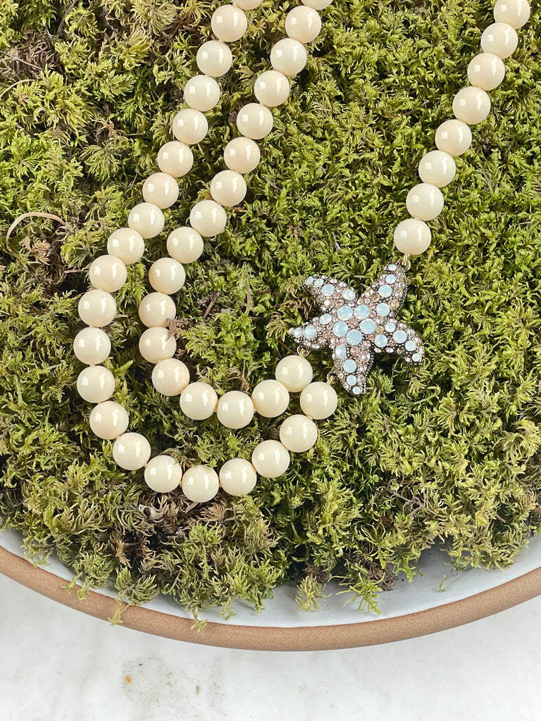 Heidi Daus double strand cream simulated pearl necklace with Swarovski crystal starfish pendant displayed outdoors