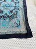 Close-up of turquoise paisley silk scarf with ornate border detailing