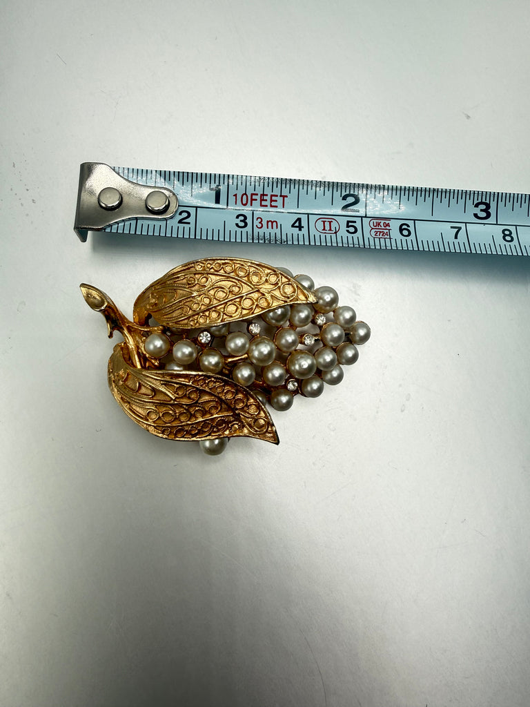Vintage faux pearl grape brooch beside measuring tape showing size