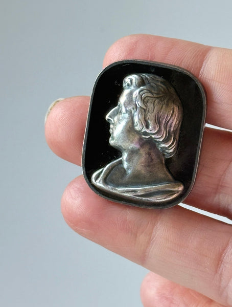 Vintage 1954 Frédéric Chopin portrait brooch with silver-tone profile on black background held in hand