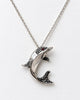 Close-up of sculptural sterling silver dolphin pendant with tiny red eye