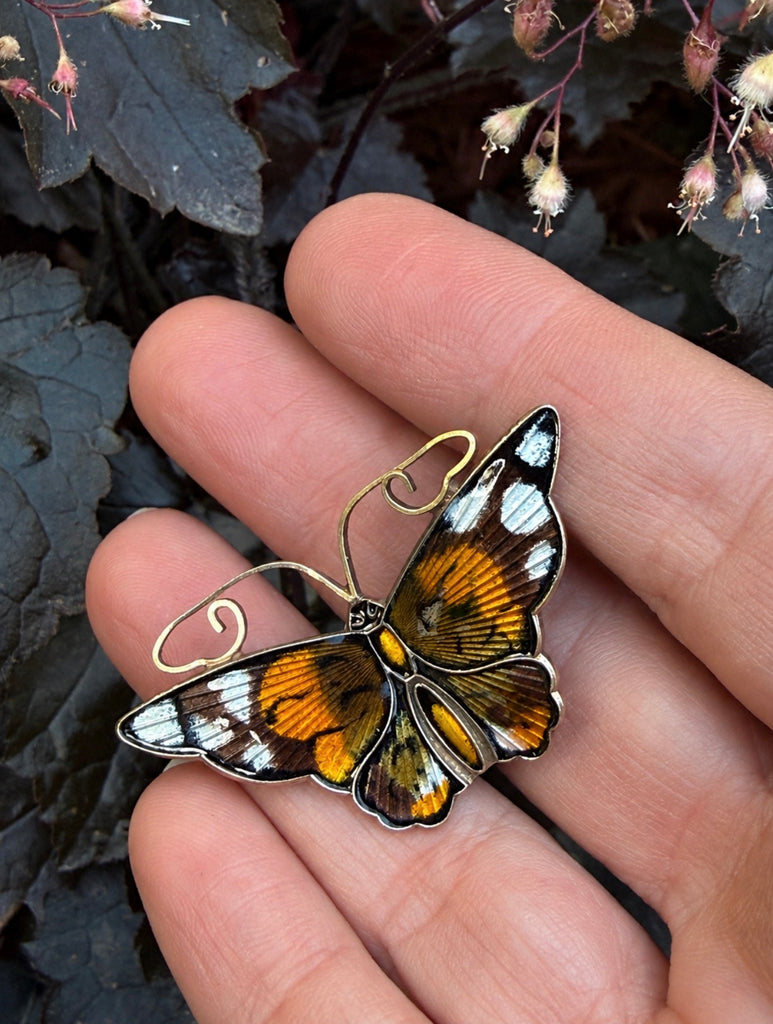Vintage Norwegian enamel Monarch butterfly brooch shown in hand for scale