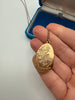 Vintage gold-filled teardrop locket held in hand showing engraved floral design