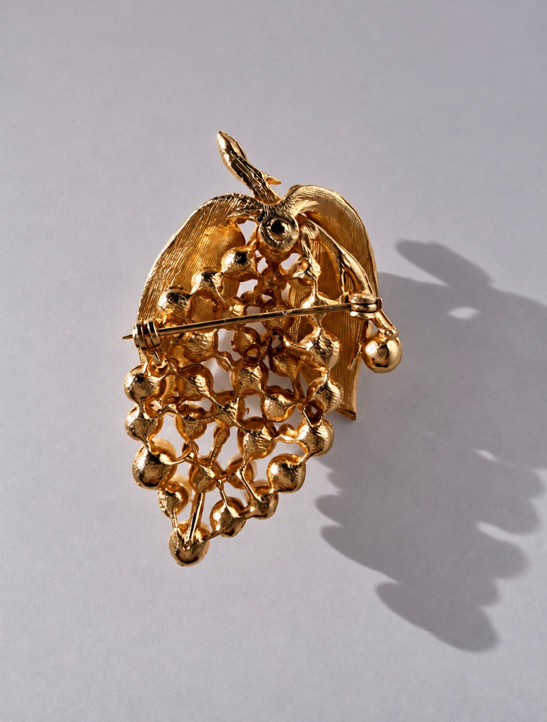 Back of vintage gold-tone grape cluster brooch showing textured leaves and pin closure