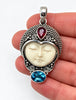 Vintage Balinese silver carved face pendant shown in hand for scale