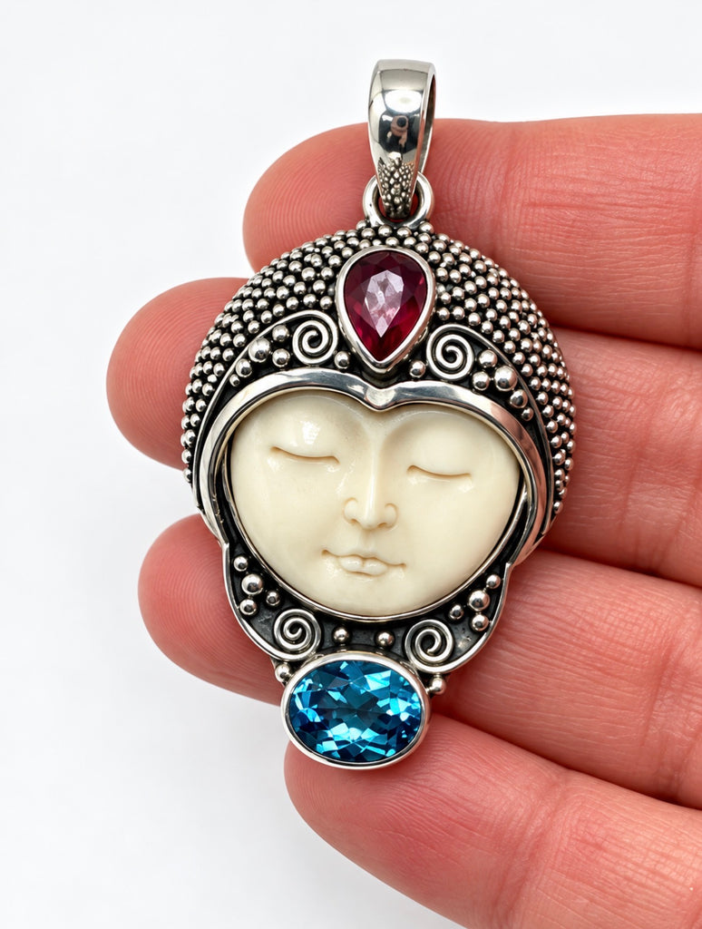 Vintage Balinese silver carved face pendant shown in hand for scale
