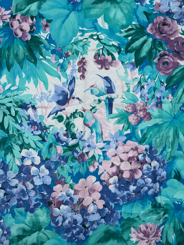 Close-up of the 1980s Liberty silk scarf showing colourful birds surrounded by lush flowers and tropical foliage. 