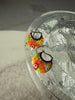 Colorful floral earrings on a clear stand with a reflective surface background