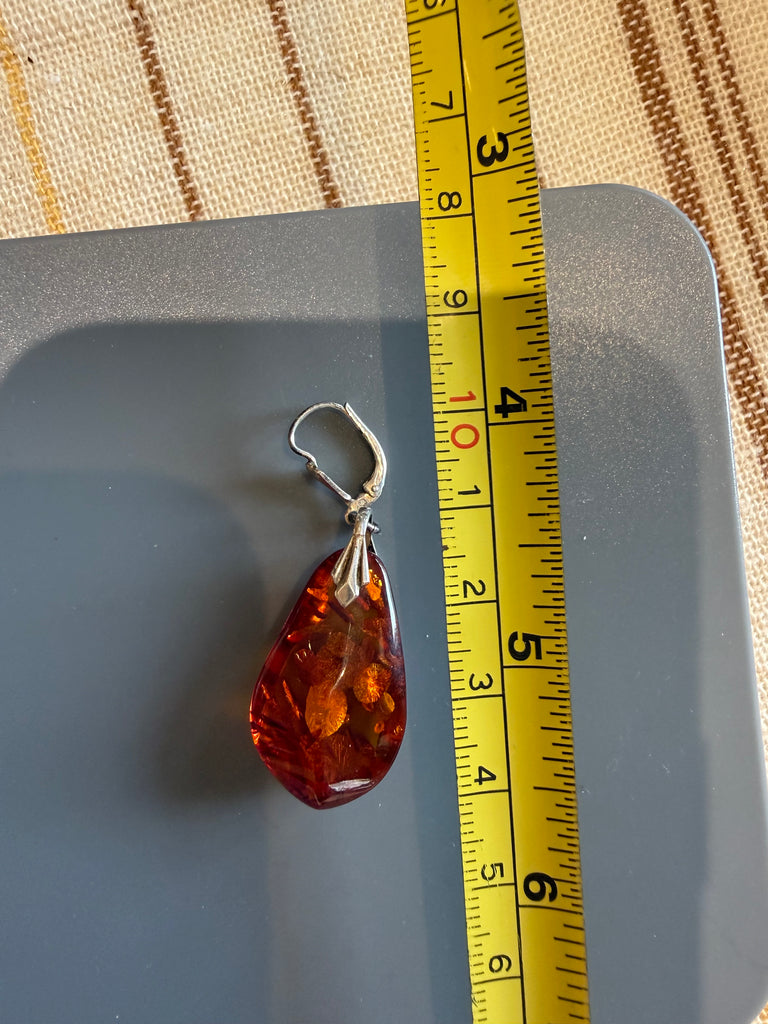 Vintage Baltic amber drop earring beside measuring tape showing approximate length