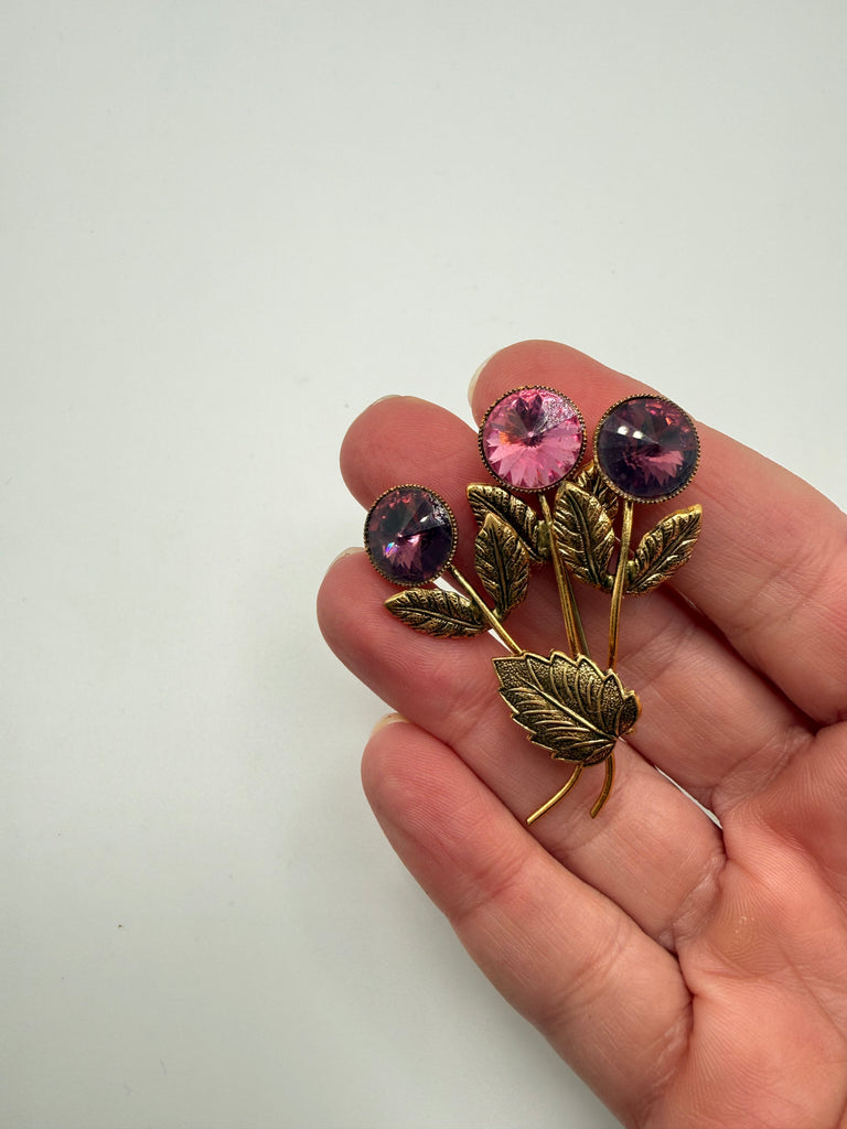 Vintage Austrian statement brooch shown in hand with pink purple crystals and textured gold-tone leaves