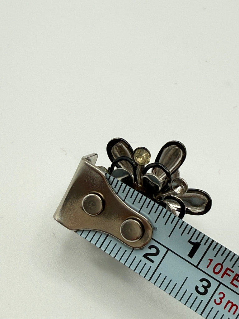Vintage floral screw back earring beside measuring tape showing approximately 2 cm width
