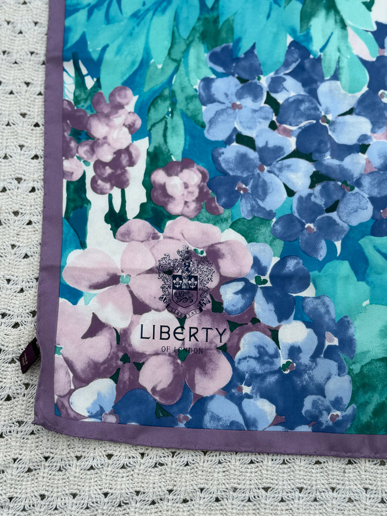 Liberty of London crest and designer signature printed on the corner of the Italian-made floral silk scarf. 