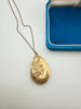 Close-up of vintage gold-filled locket with engraved flowers and leaves
