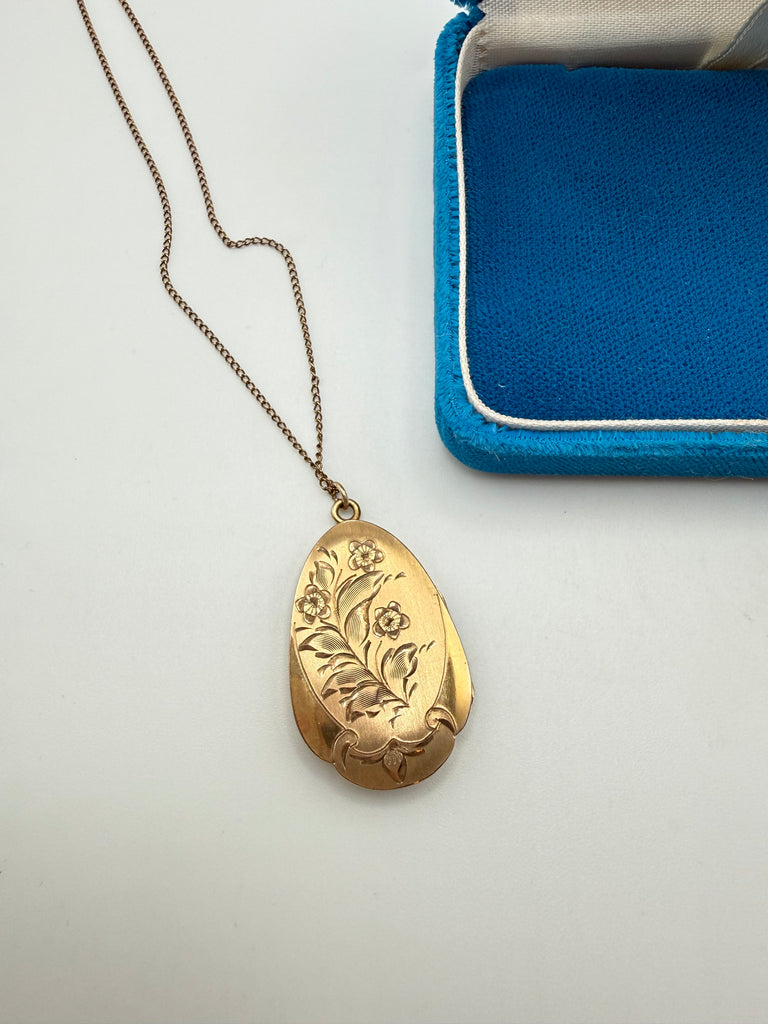 Close-up of vintage gold-filled locket with engraved flowers and leaves