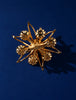 Back of vintage gold-tone faux pearl flower brooch showing pin closure