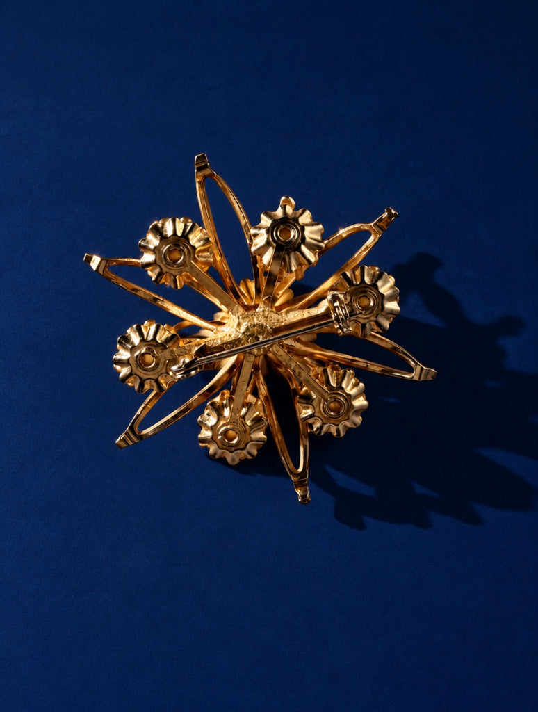 Back of vintage gold-tone faux pearl flower brooch showing pin closure