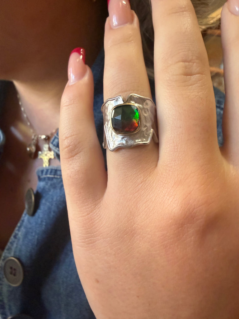 Ammolite sterling silver ring worn on finger showing bold wide-band statement design