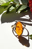 Close-up of polished orange Baltic amber cabochon in gold-plated silver setting