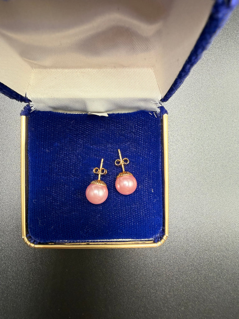 Pink faux pearl stud earrings with gold-tone posts displayed in open jewellery box