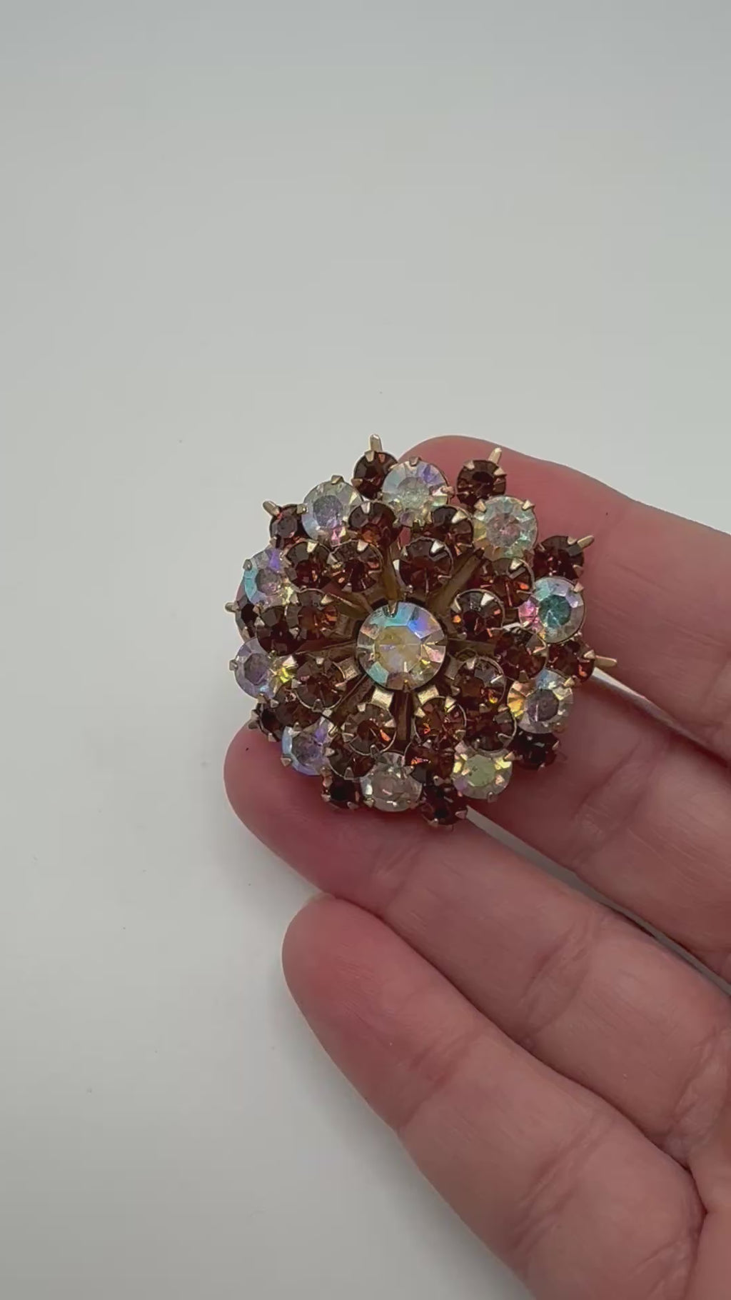 Aurora Borealis crystal and amber rhinestone starburst brooch shown in hand for scale