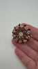 Aurora Borealis crystal and amber rhinestone starburst brooch shown in hand for scale