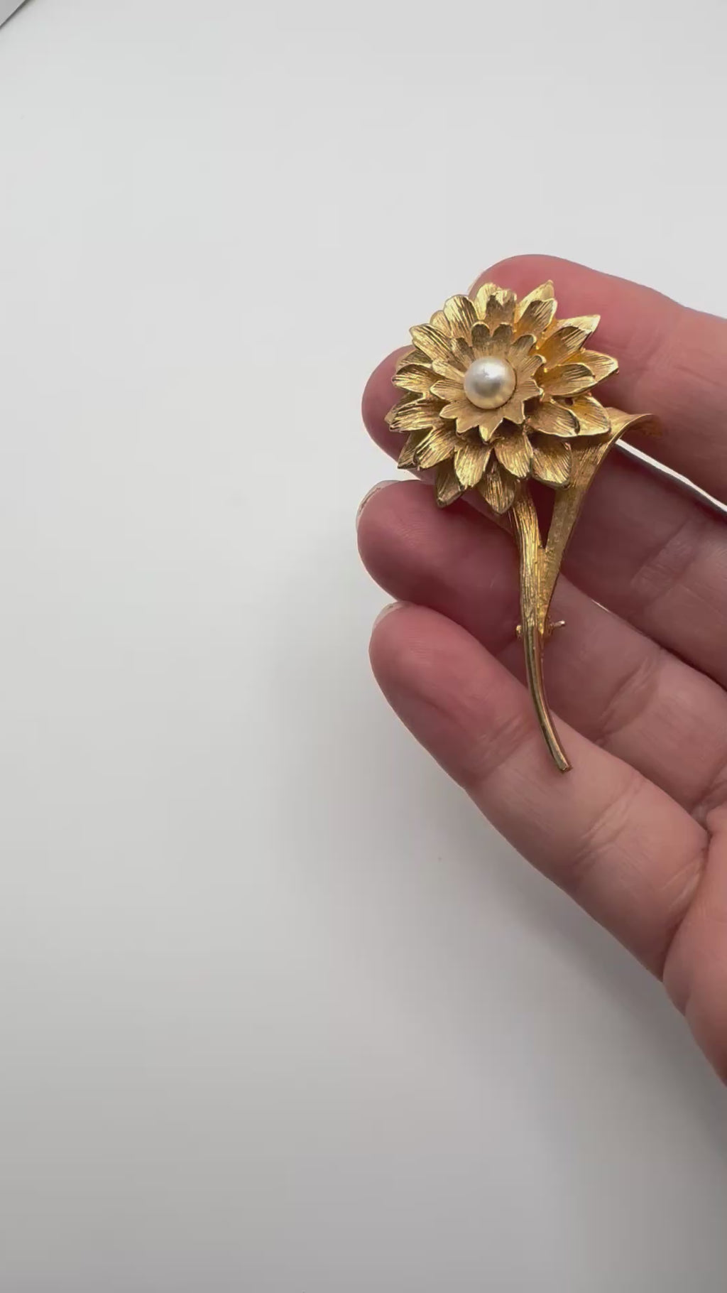 Large vintage gold tone floral brooch with faux pearl centre shown in hand for scale