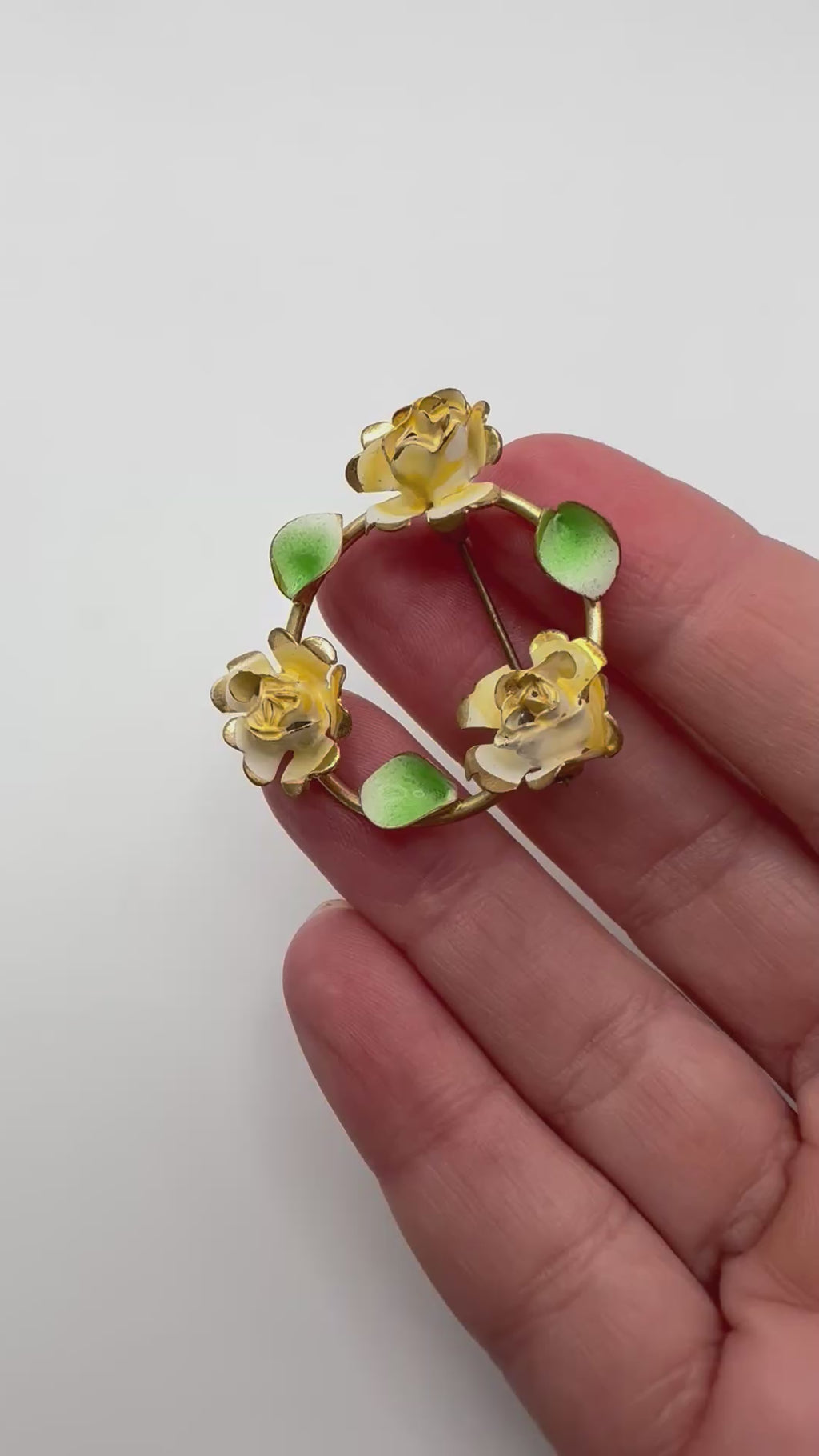 Yellow rose enamel wreath brooch shown in hand for scale